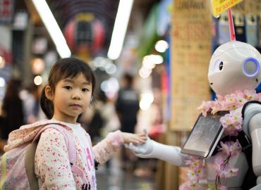 Photo of a child holding hands with a robot